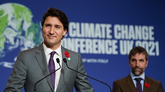 Prime Minister Justin Trudeau smiles at a podium as Minister Steven Guilbeault looks on