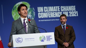 Prime Minister Justin Trudeau stands at a podium as Minister Steven Guilbeault looks on