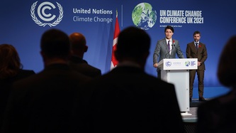 Prime Minister Justin Trudeau stands at a podium as Minister Steven Guilbeault looks on