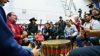 Des gens sont assis autour d'un tambour, et chantent