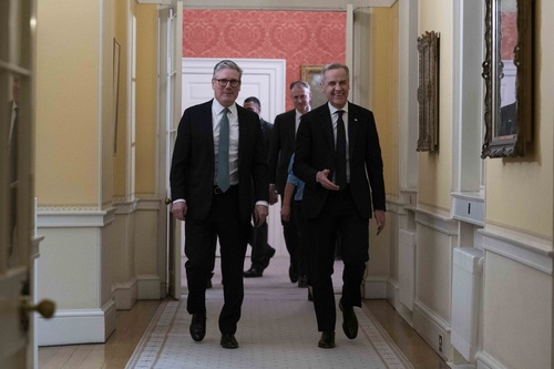 Prime Minister Mark Carney walks down a hallway with Prime Minister Sir Keir Starmer at 10 Downing Street.