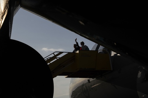 The silhouettes of Prime Minister Carney and Diana Fox Carney waving as they board an aircraft in Amsterdam.