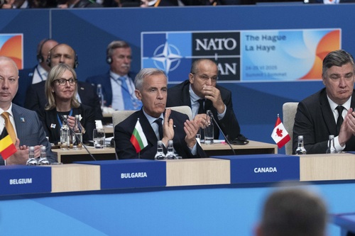 Prime Minister Carney and other world leaders are sitting and applauding during a meeting at the NATO Summit.