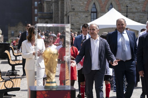Prime Minister Carney looks at the FIFA World Cup trophy with members of staff and the youth soccer team on Parliament Hill.