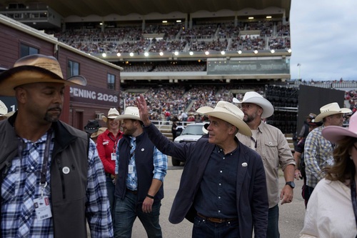 Prime Minister Carney walking and waving to a crowd at the Calgary Stampede.