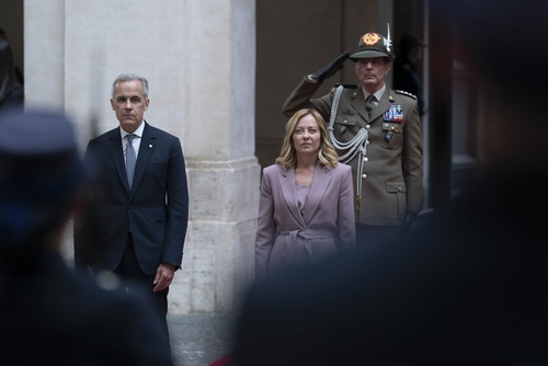 Prime Minister Mark Carney stands outside Chigi Palace with Prime Minister Giorgia Meloni in front of a group of guards. 