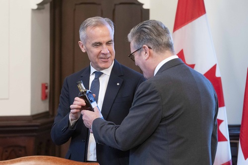 Prime Minister Mark Carney and Prime Minister Sir Keir Starmer hold a bottle of maple syrup in West Block on Parliament Hill.