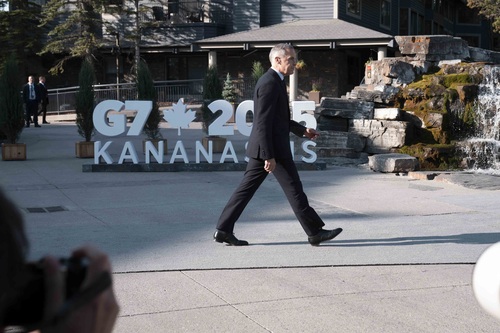 Prime Minister Mark Carney walking by the “G7 2025 Kananaskis” sign. 