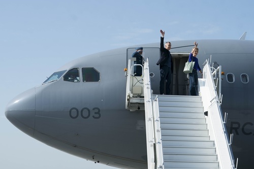 Prime Minister Mark Carney and Diana Fox Carney waving as they board an aircraft in Calgary, Alberta. 