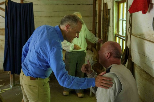 Prime Minister Mark Carney greeting a man inside a house at the Village Historique Acadien.