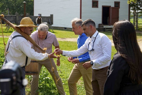 A farmer at the Village Historique Acadien shows Prime Minister Mark Carney and others some harvested yellow string beans. 