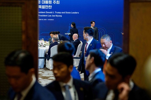 Out of focus in the foreground, a group of people stand at an entryway of the working dinner hosted by the President of th...