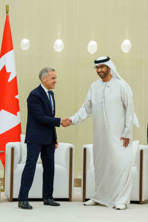 Prime Minister Mark Carney stands and shakes hands with UAE’s Minister of Industry and Advanced Technology, His Excellency...