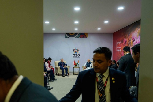 Un groupe d’hommes est debout à l’entrée d’une salle où se tient une rencontre bilatérale entre le premier ministre Mark C...