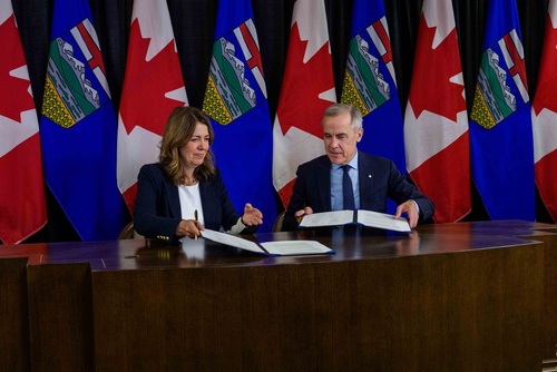 Le premier ministre Mark Carney et la première ministre de l’Alberta, Danielle Smith, échangent des documents durant la cé...
